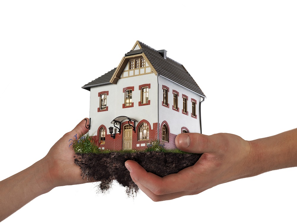 Hands Holding A House. The Concept Of Relocation Mortgage Inheritance